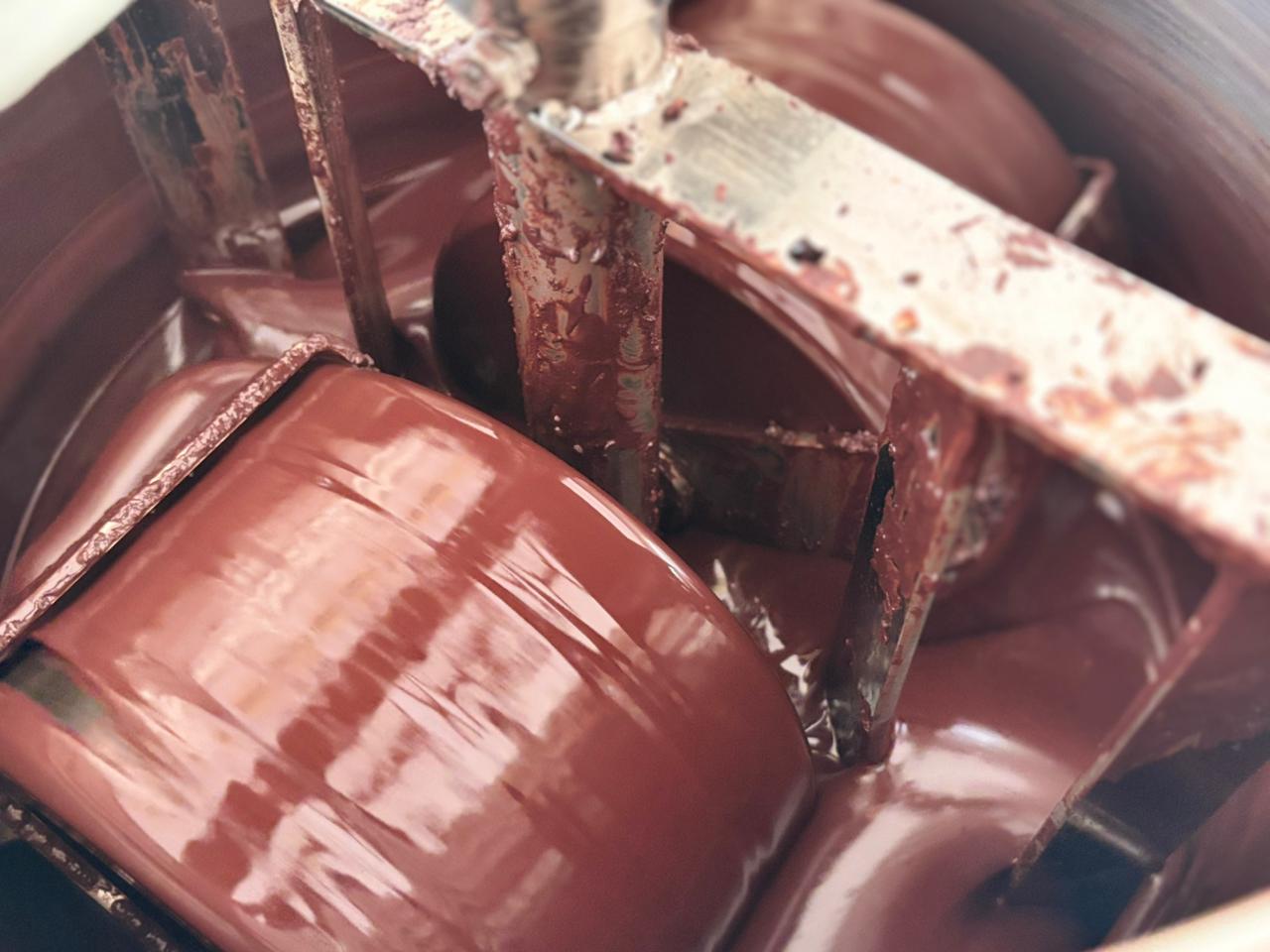 Stone grinders (melangers) processing raw cacao nibs into smooth cacao mass